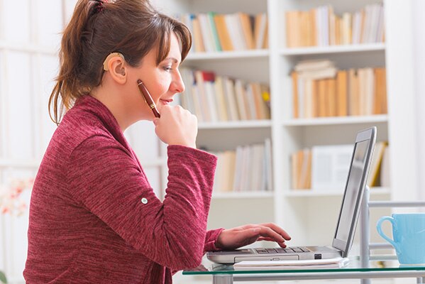 Woman wearing hearing aid working at laptop