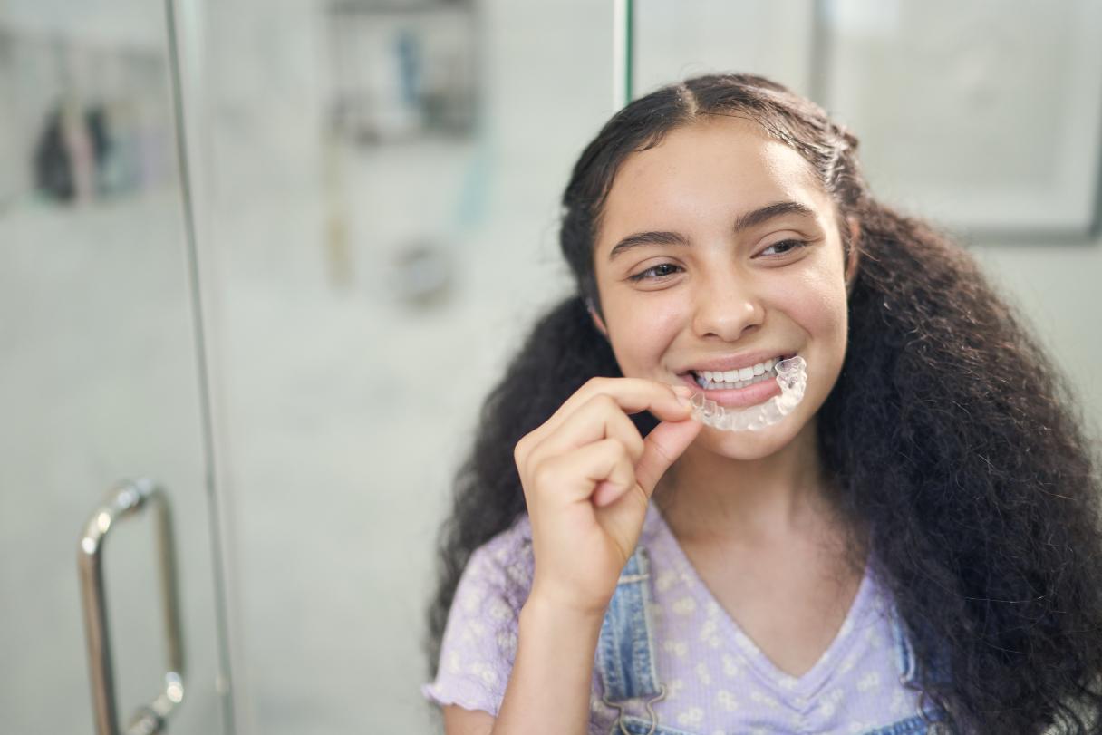 Smiling girl taking aligner tray out of her mouth