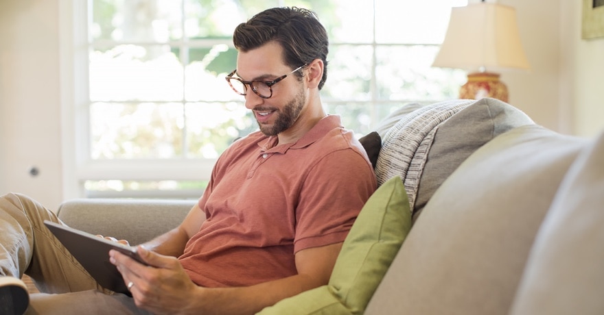 Man sitting  on couch, looking at tablet screen