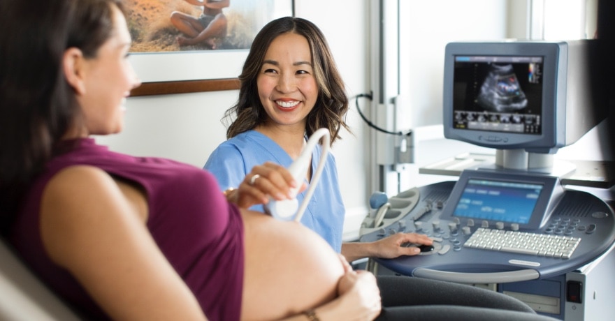 Nurse providing ultrasound on pregnant woman, both smiling