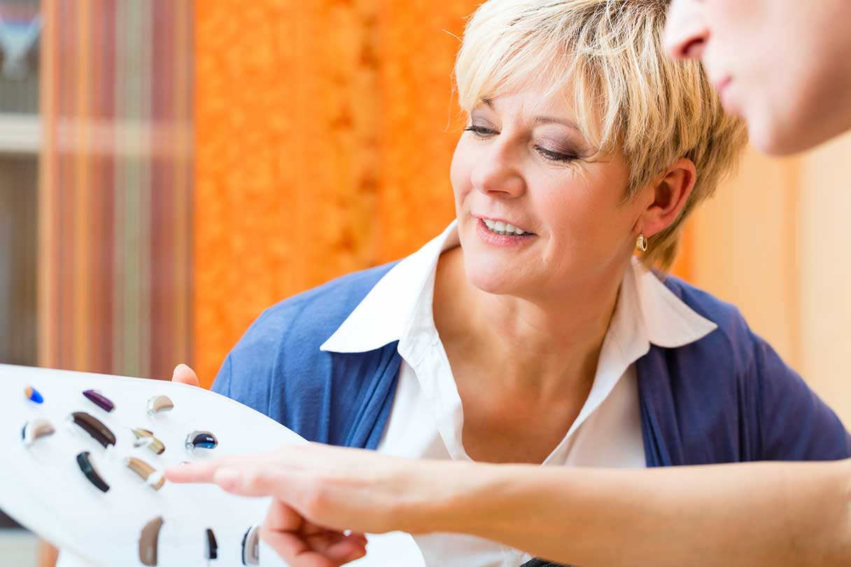 Two people assessing different hearing aid options