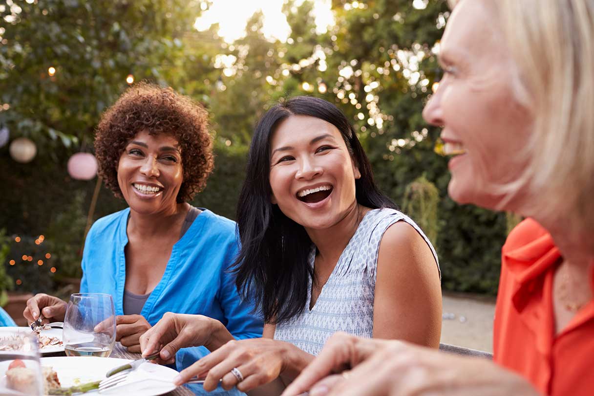 Group of women eating outside and laughing together