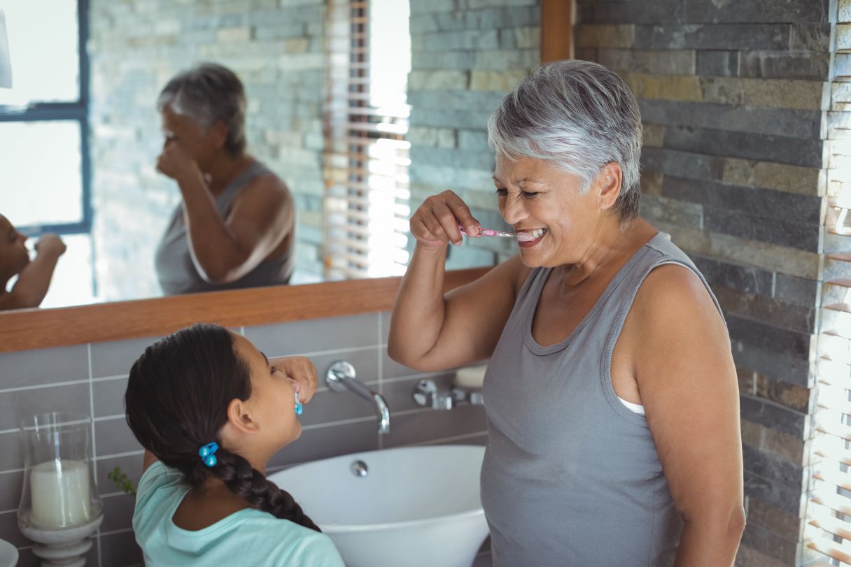 Senior woman and young girl brushing their teeth together