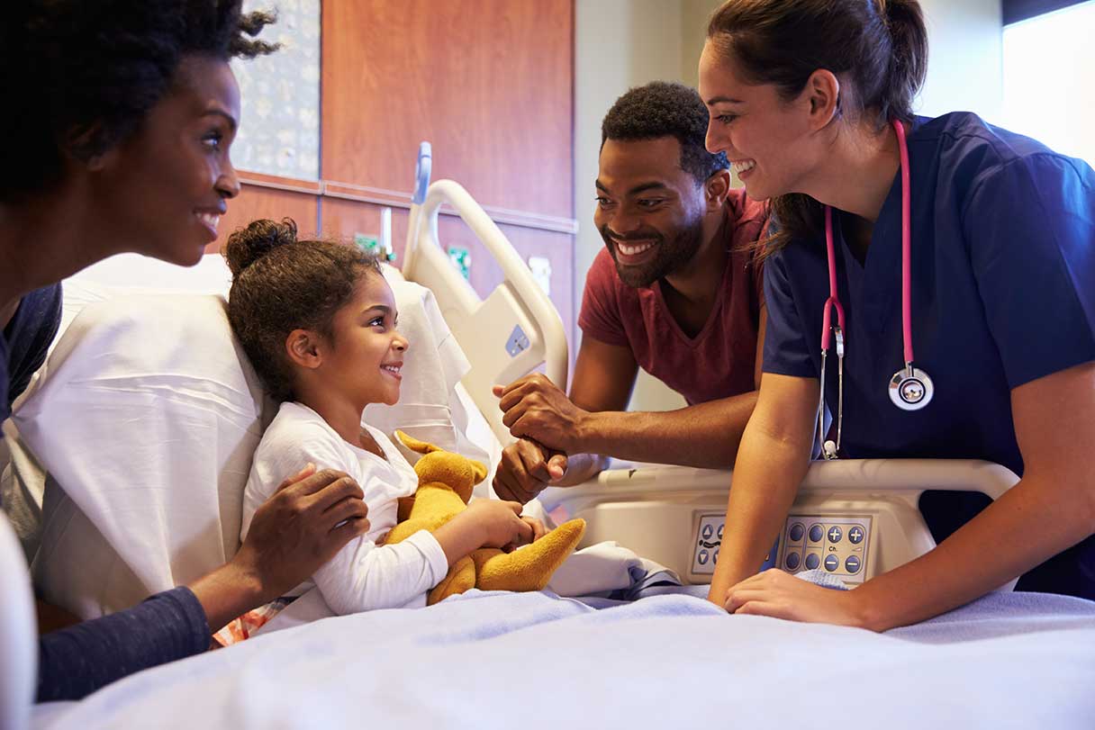 Healthcare professionals speaking to a young girl in a hospital bed