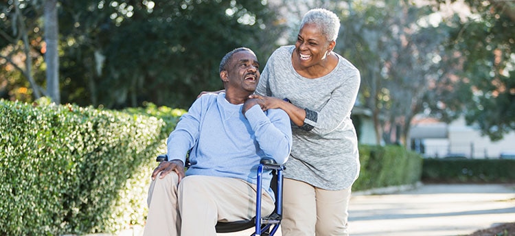 Smiling man in wheelchair with woman behind him