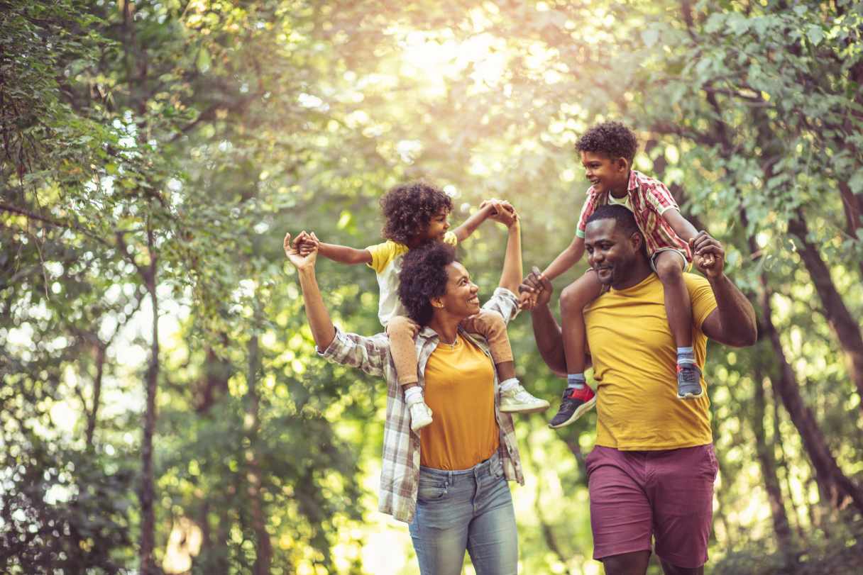 Man and woman with children on their shoulders, walking outside