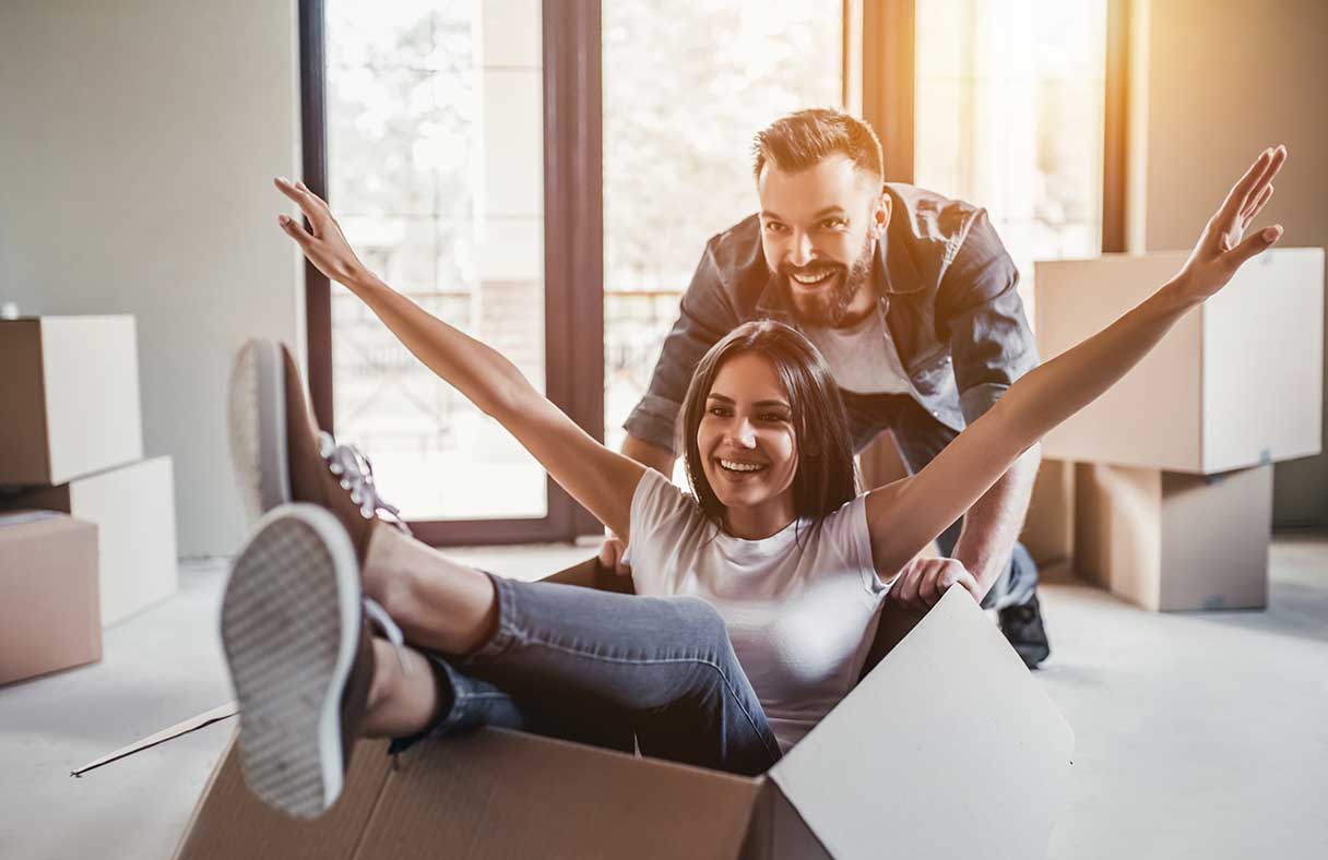 Man pushing woman in a box, both smiling