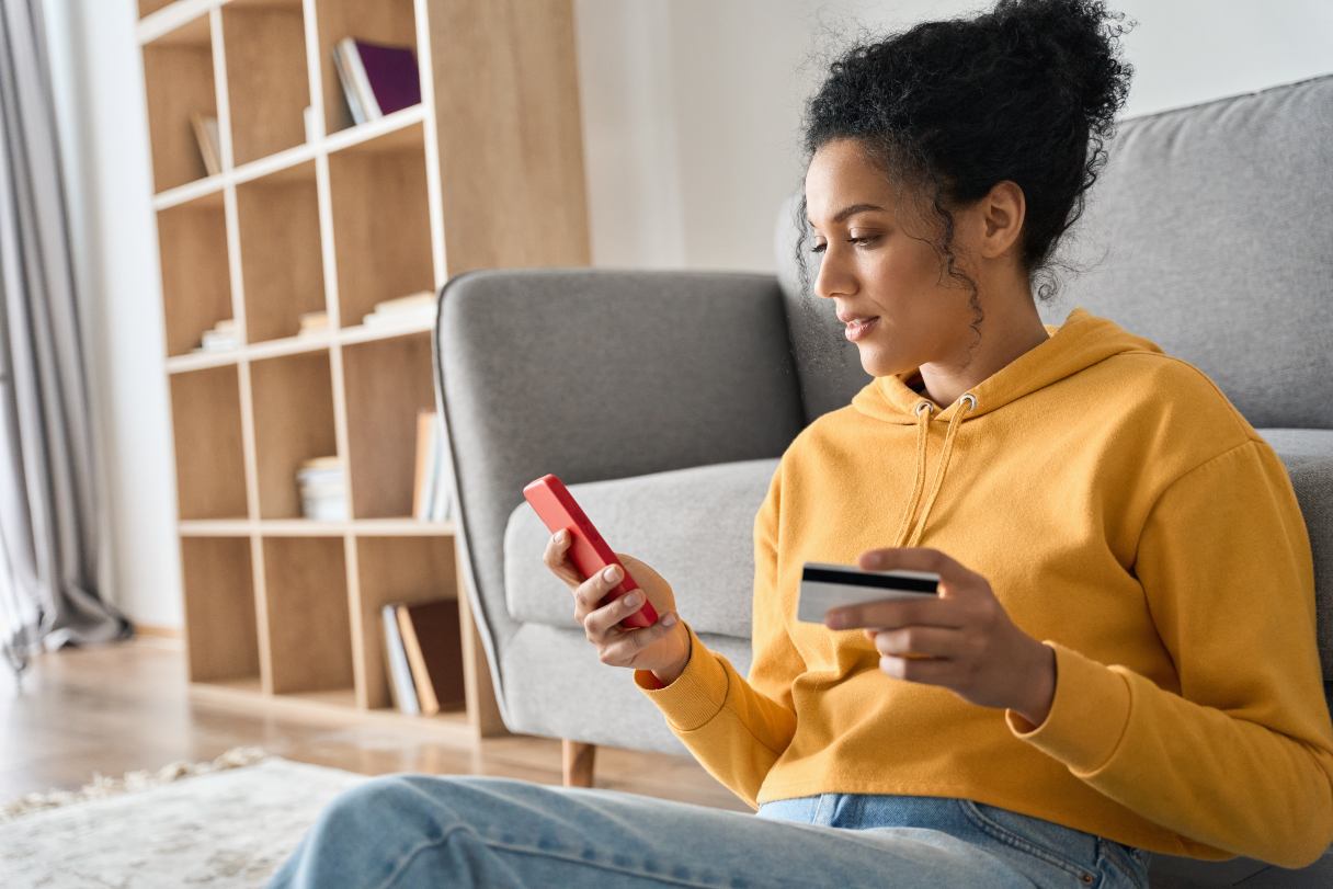 Woman looking at her phone while holding her credit card