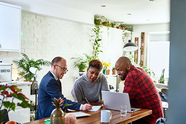 Group of people working a table with laptop and papers between them