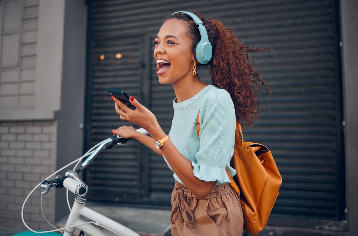 Smiling woman with headphones on, sitting on bike