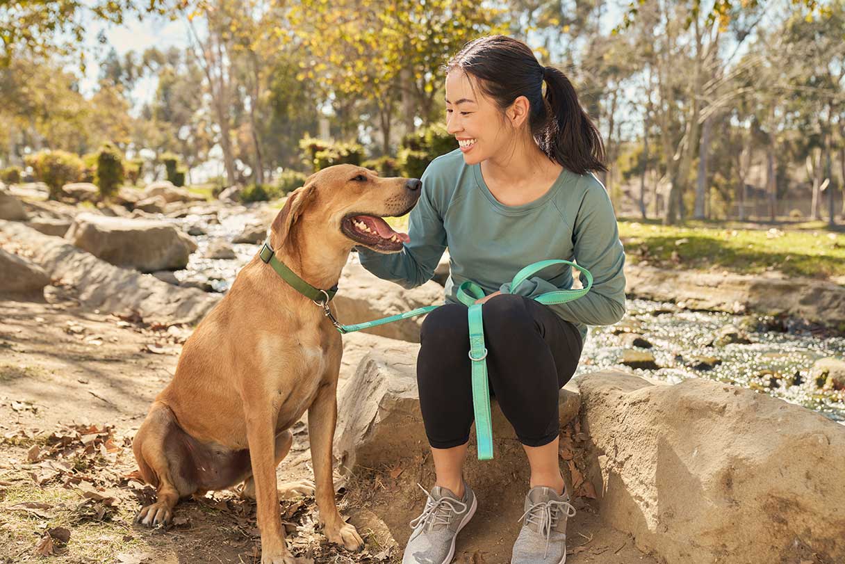 Smiling woman sitting outside with a dog