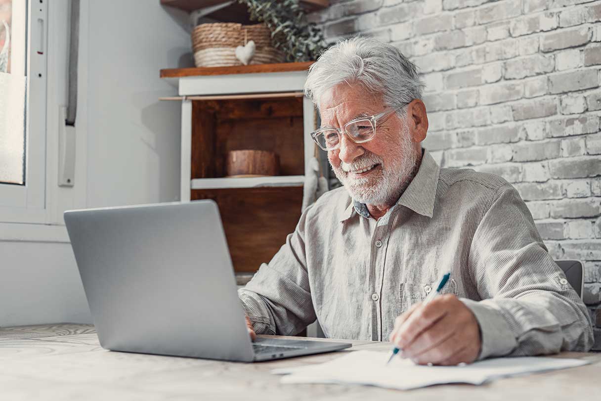 Senior man in glasses working at laptop