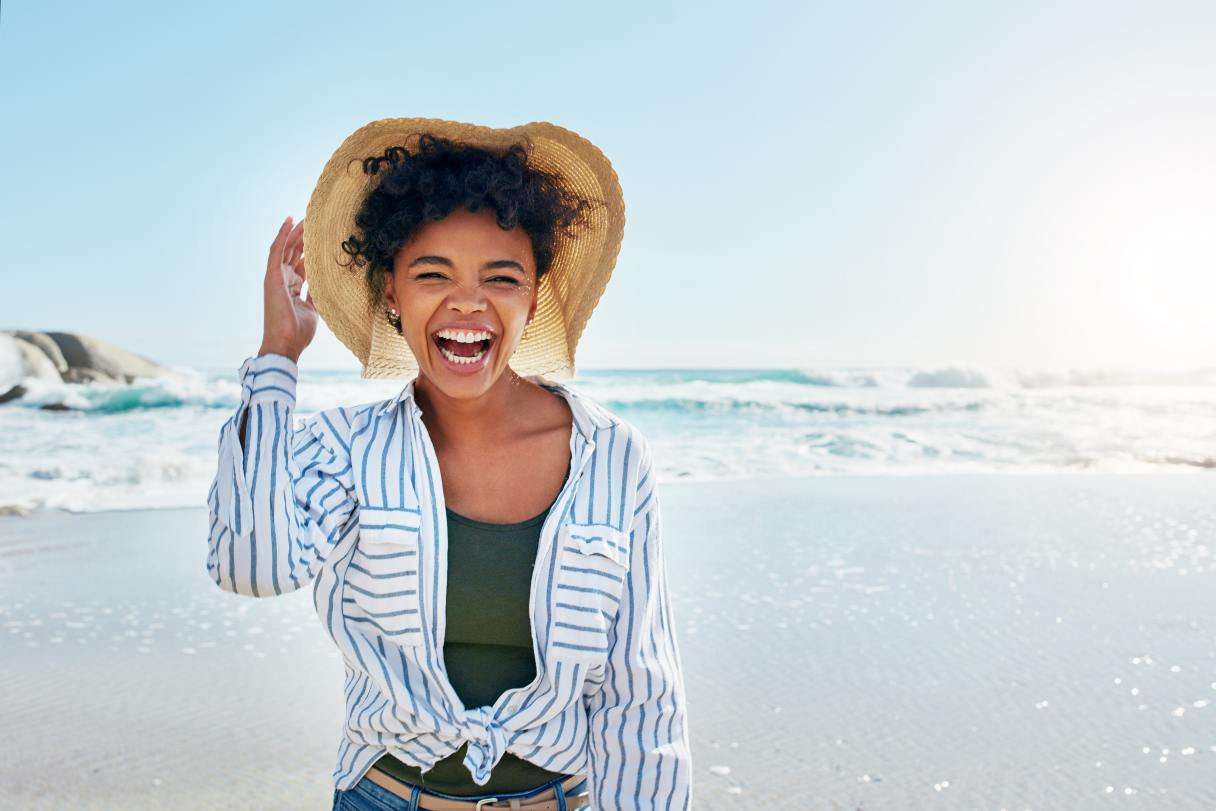 Laughing woman in hat, walking on beach 