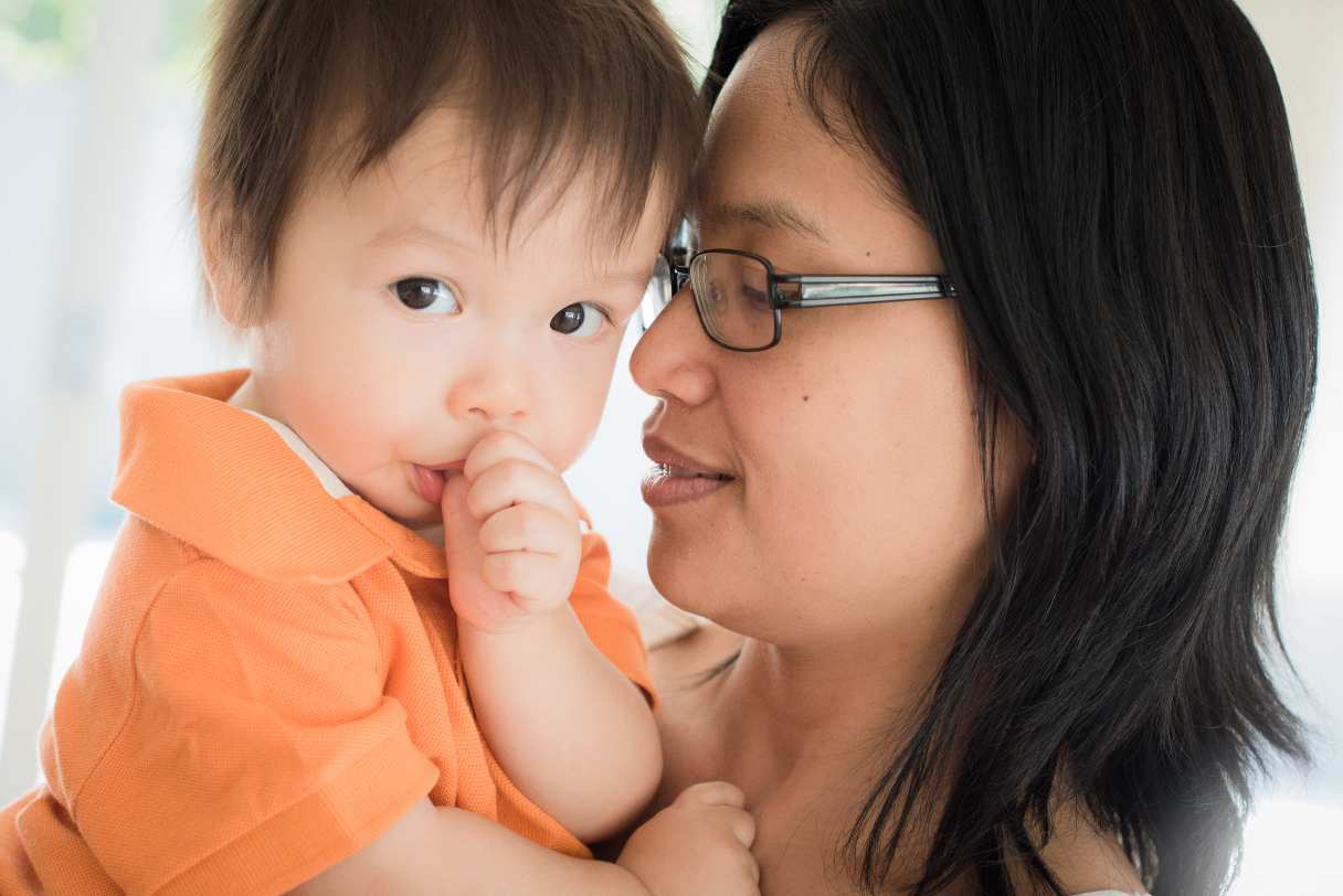 Woman holding an infant who is sucking their thumb