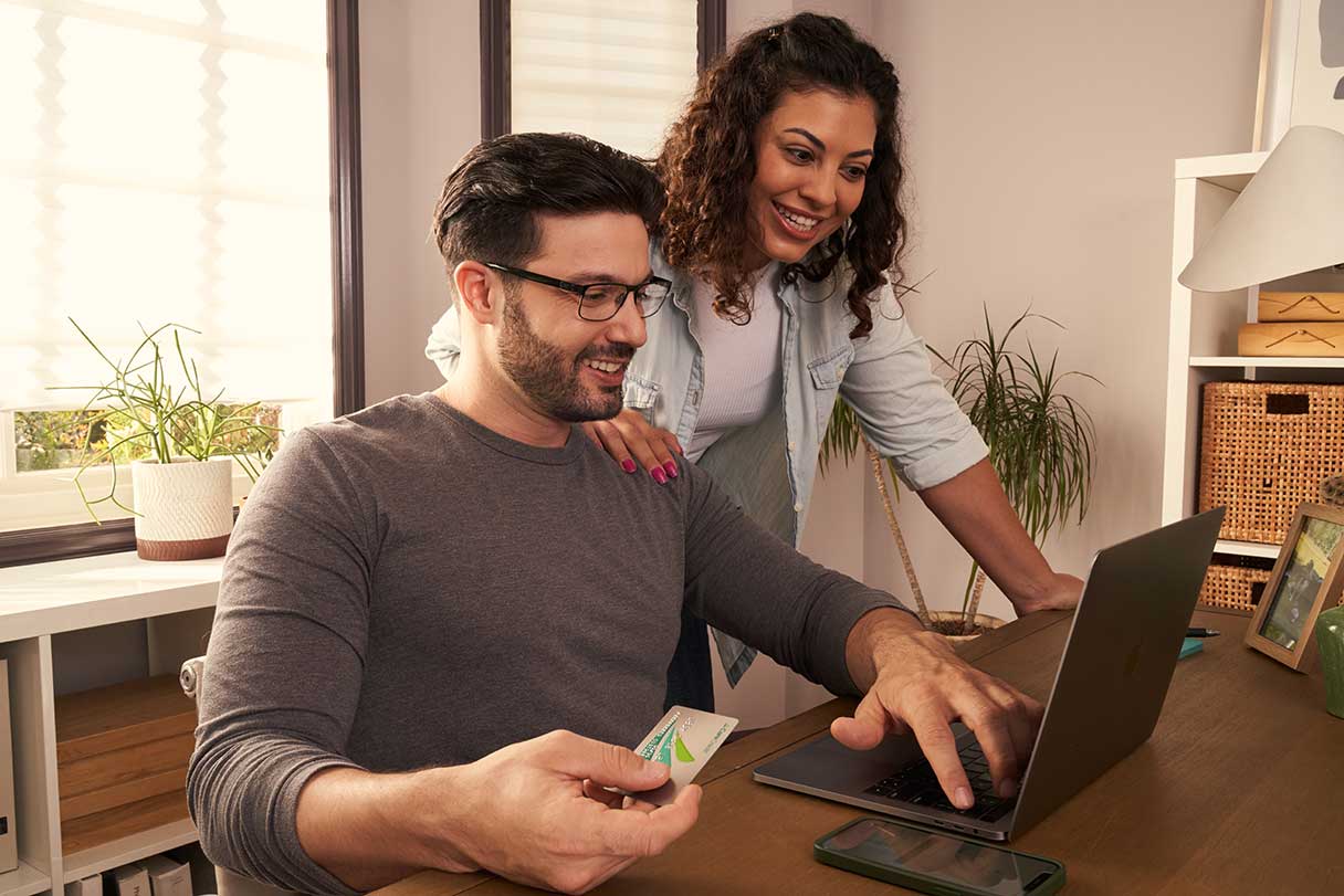 Man and woman with CareCredit credit card on working on laptop