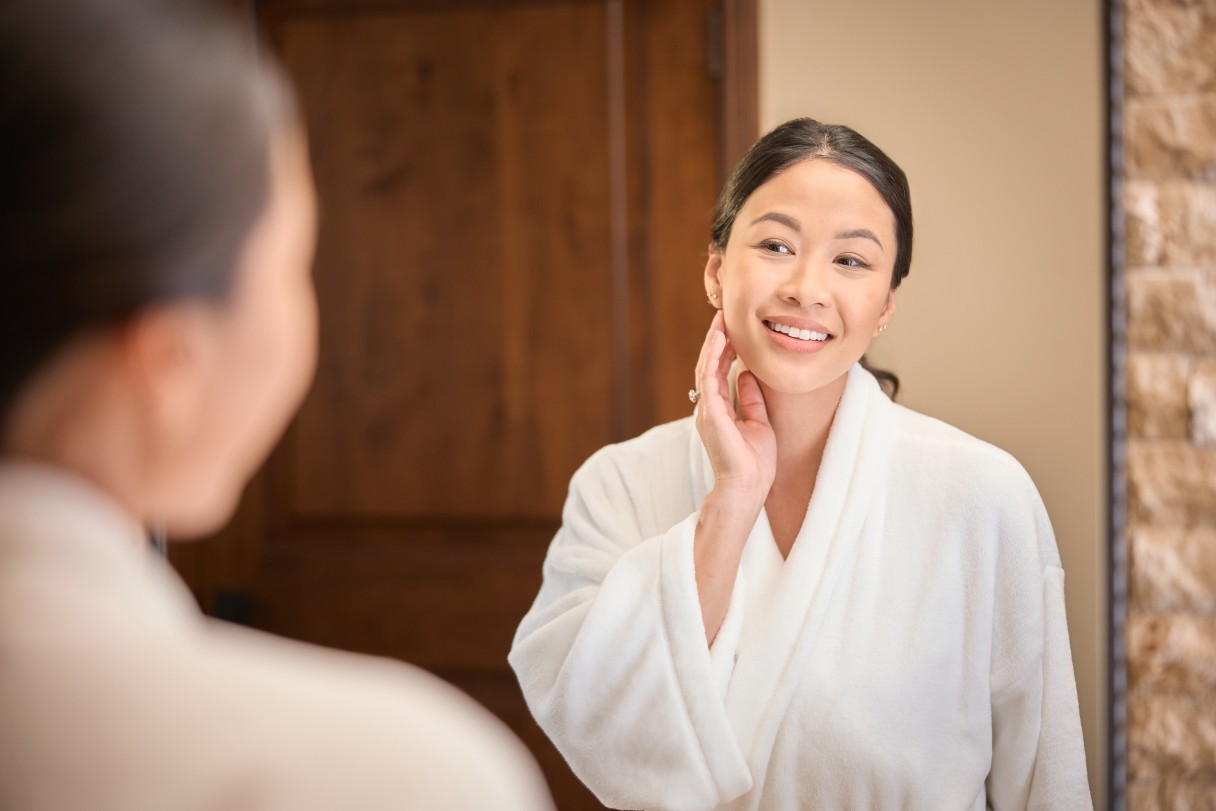 Woman applying product to her face while looking in a mirror
