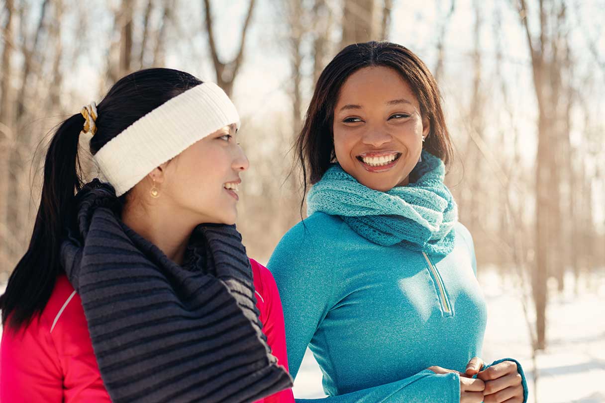 Two women walking outside together in the snow, wearing workout clothes