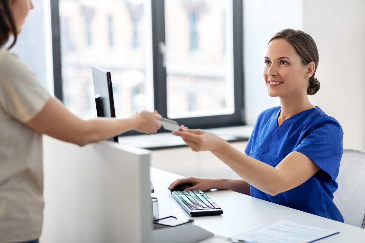 Medical receptionist passing credit card back to patient