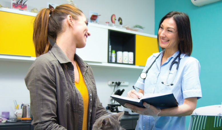 Woman with cat speaking to veterinarian