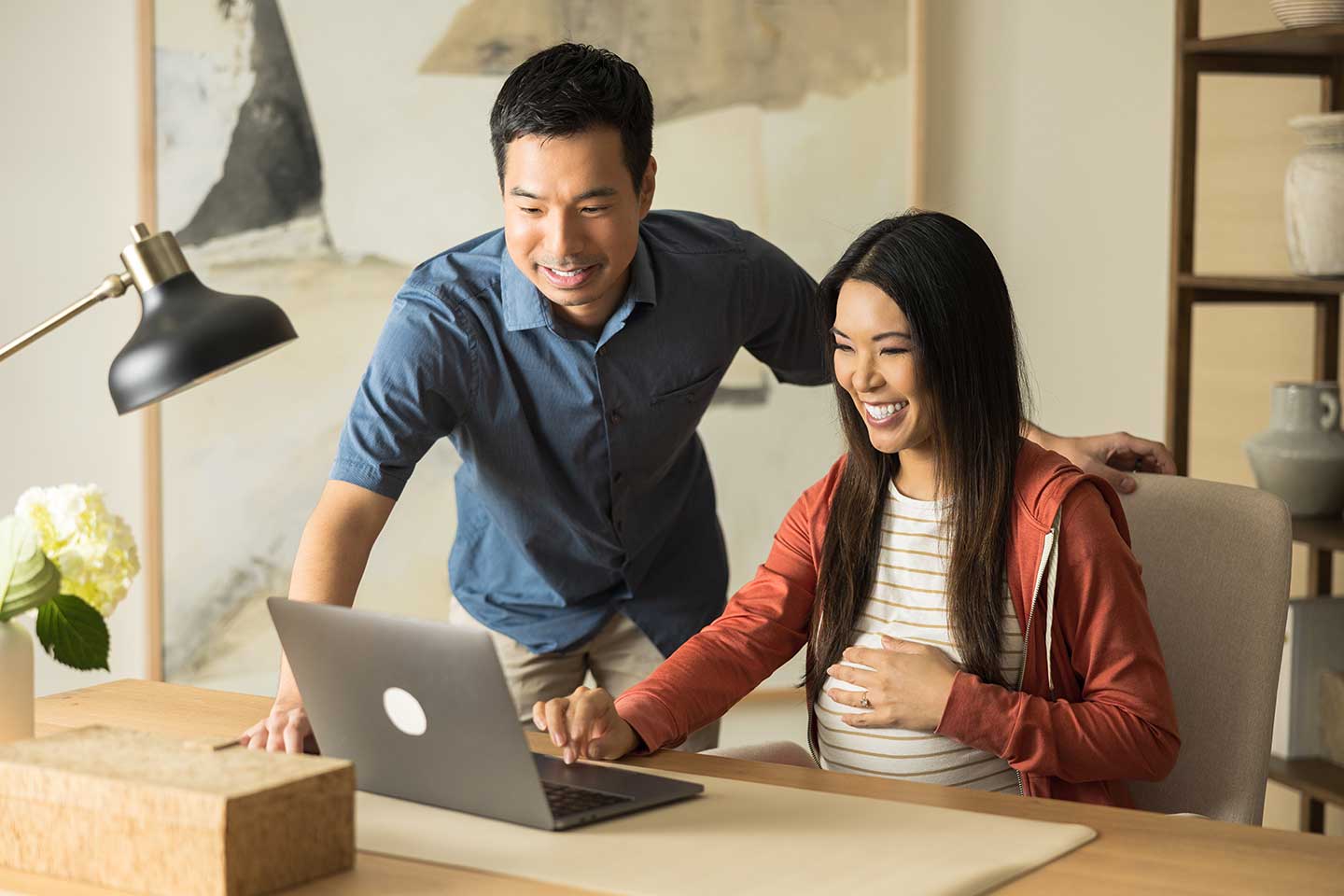 Pregnant couple working at a laptop