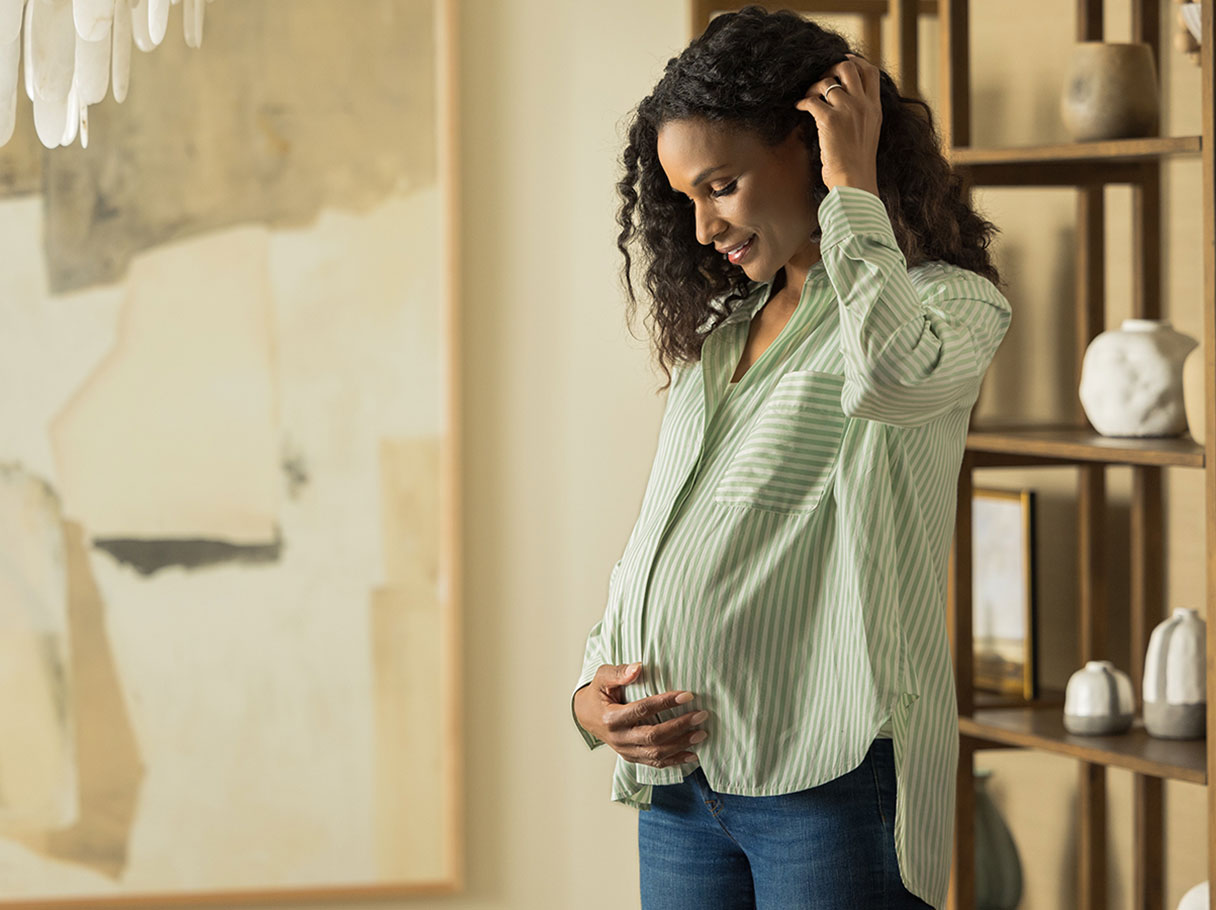 Smiling pregnant woman holding her stomach